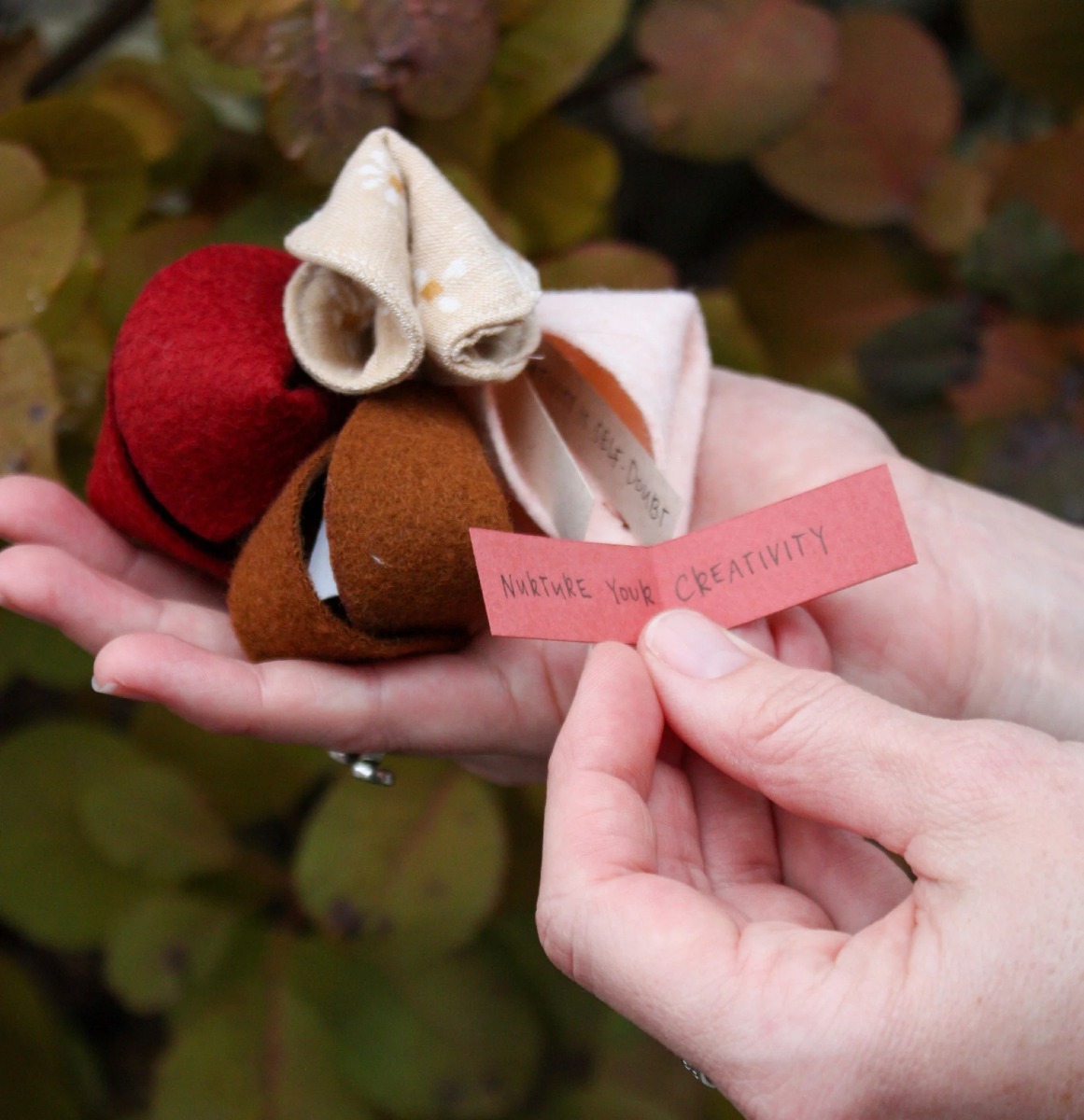 A handful of felt fortune cookies with one unfolded fortune that reads, “Nurture your creativity.”