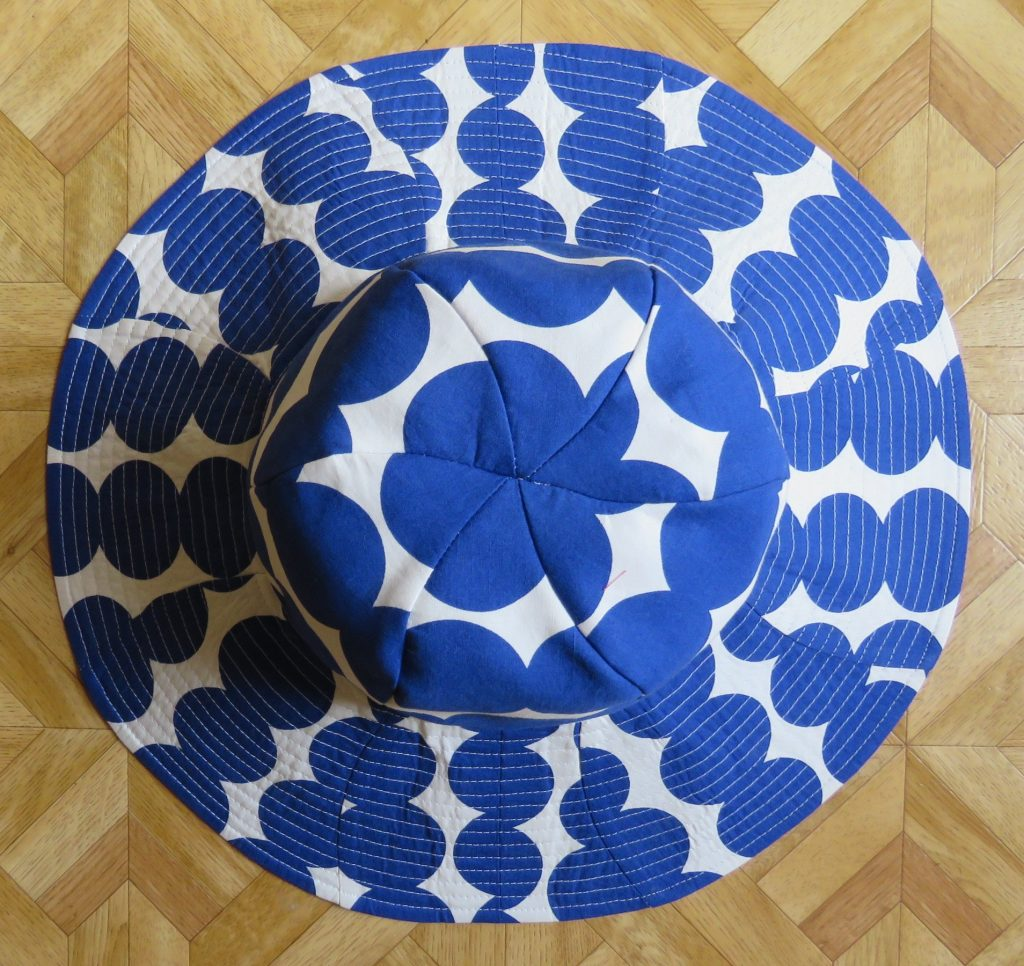 Top down image of the sunhat on a flat surface. Seams showing the hat construction are clearly visible and highlight the unusual shape of the pattern pieces.